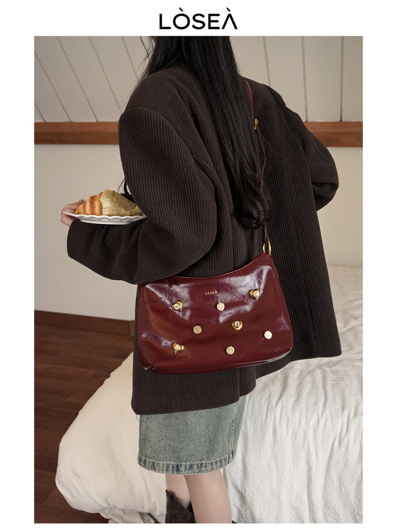Woman wearing a burgundy shoulder bag with a dark oversized sweater and denim skirt