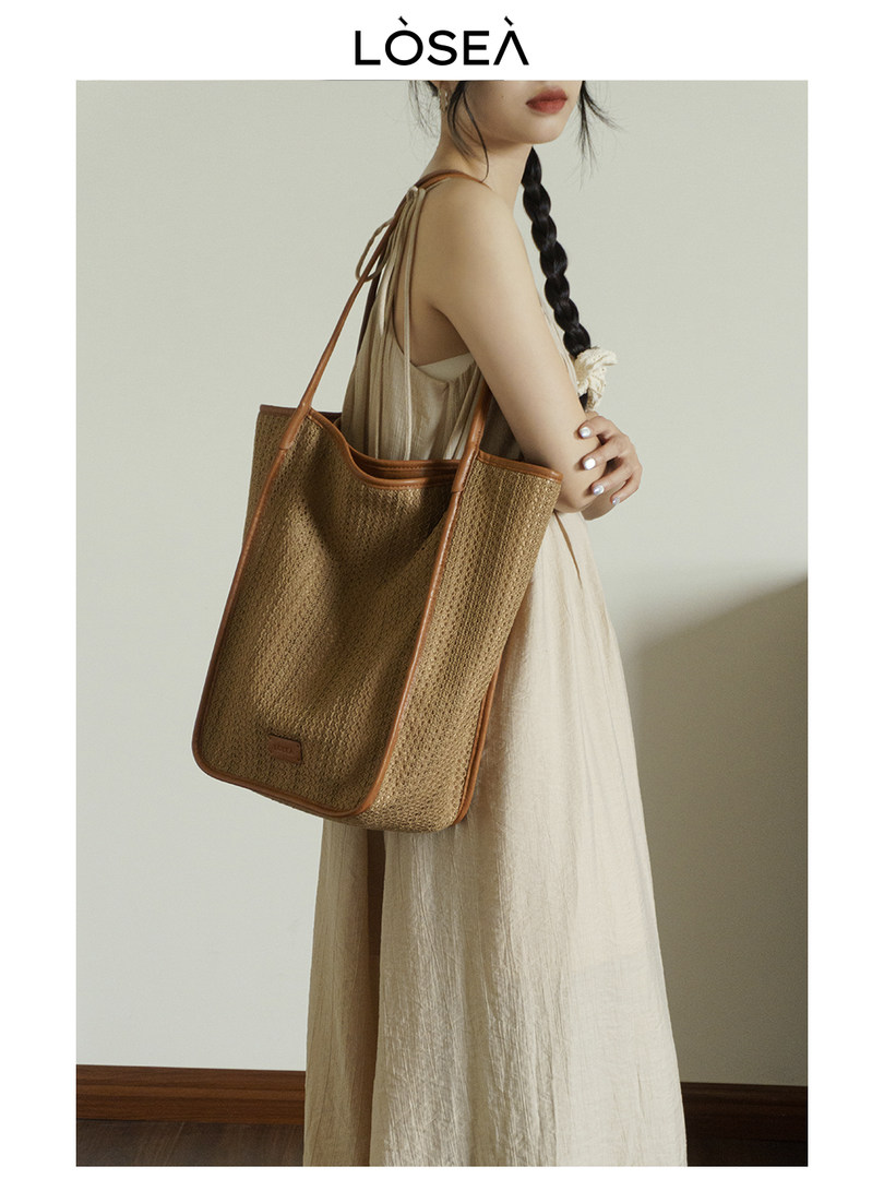 Model wearing a woven tan tote bag