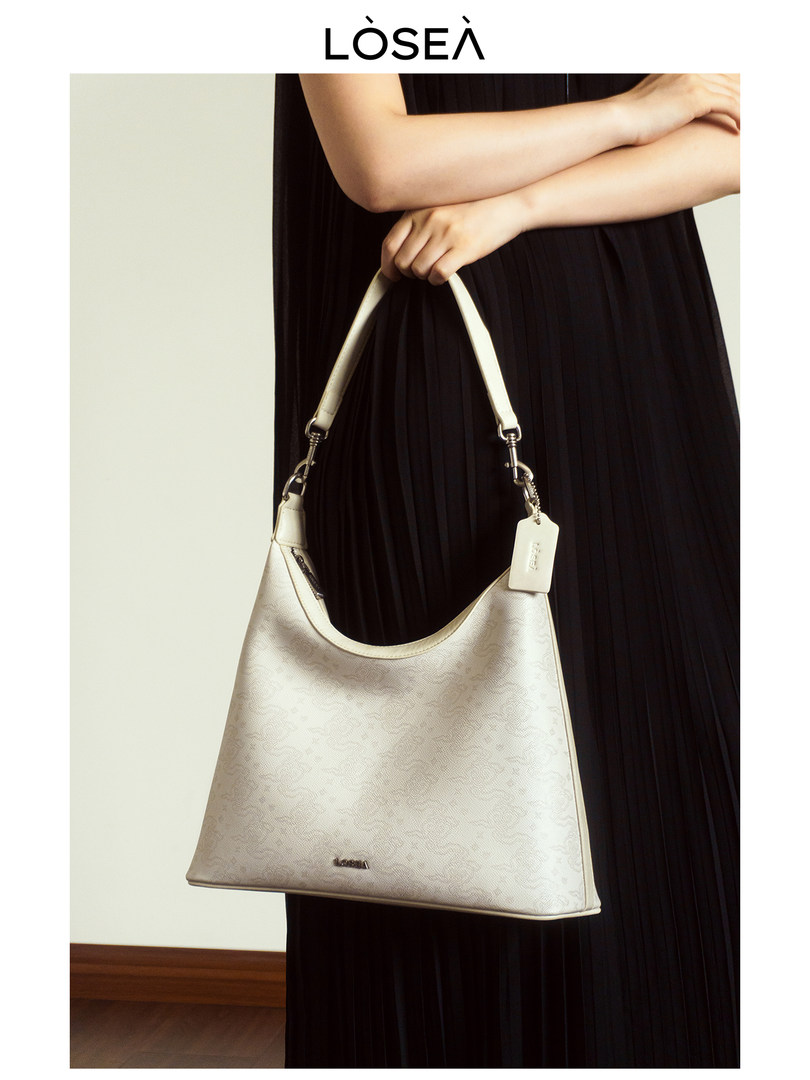 Light-colored leather shoulder handbag held by a model