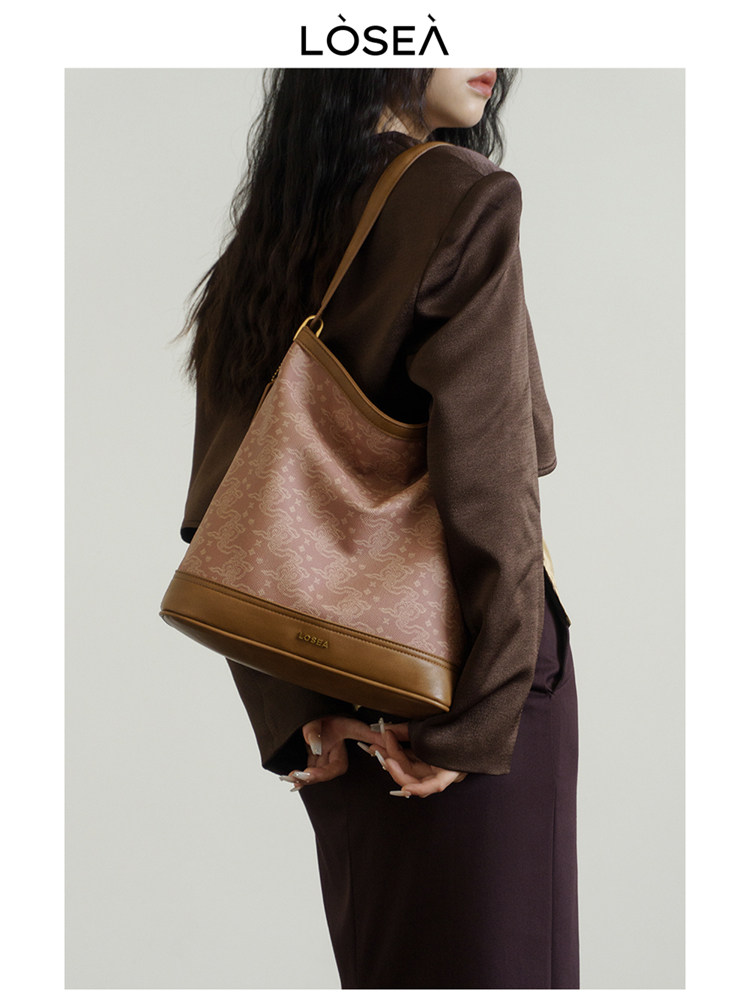 Brown shoulder bag worn by a model on a studio background