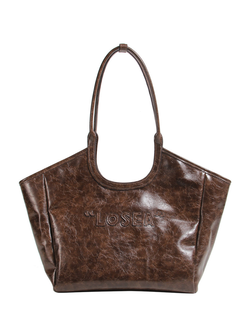 Brown faux leather tote handbag with long handles on a white background