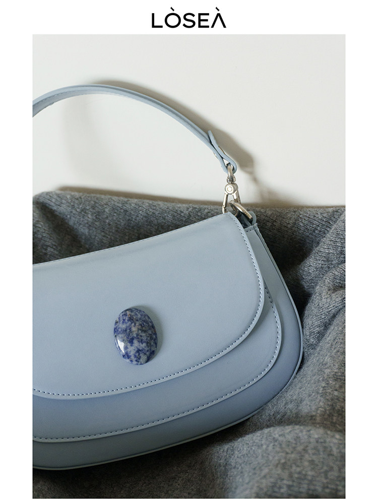 Light blue leather handbag with shoulder strap on a fabric background