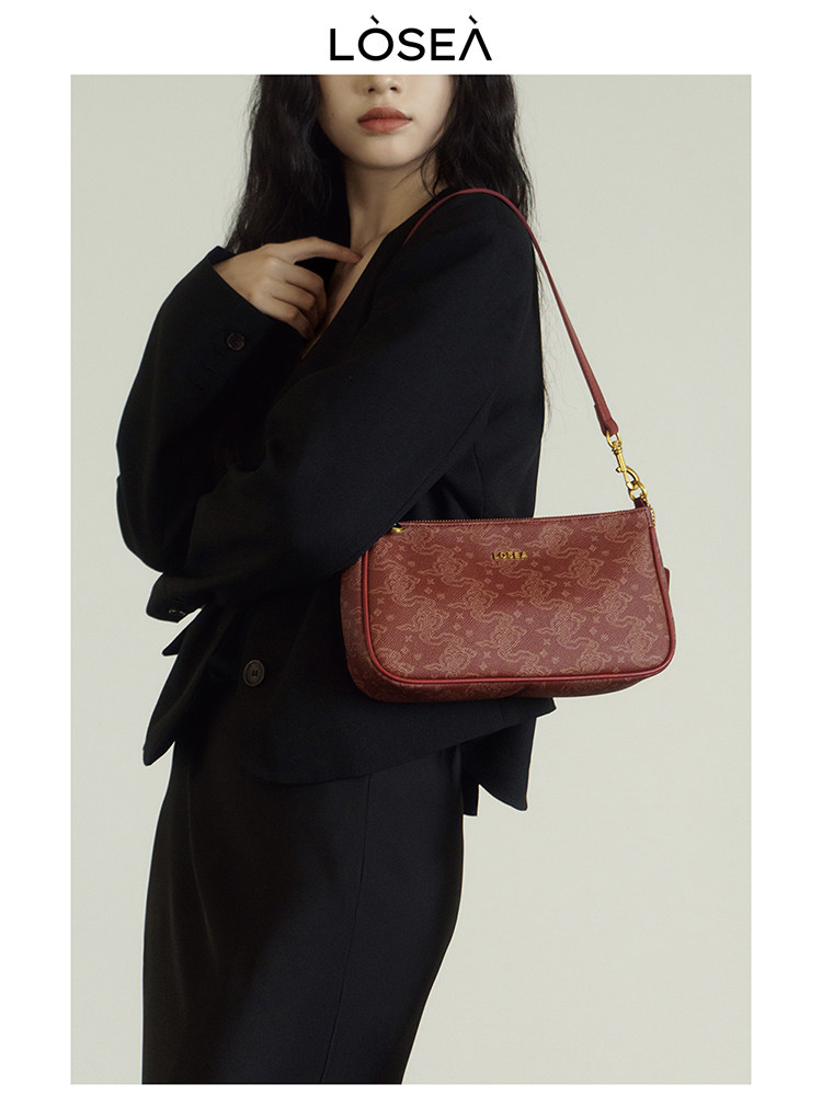 Red patterned shoulder handbag worn by a model with a black outfit