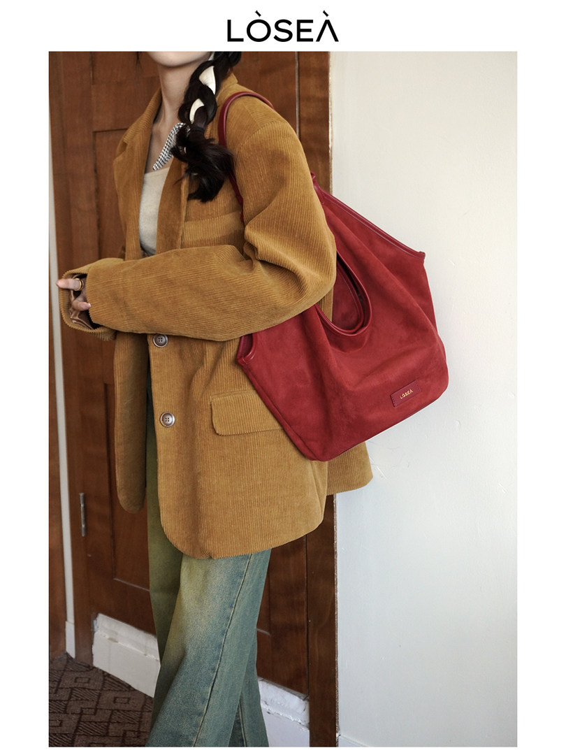 Woman wearing a mustard corduroy blazer with a large red tote bag