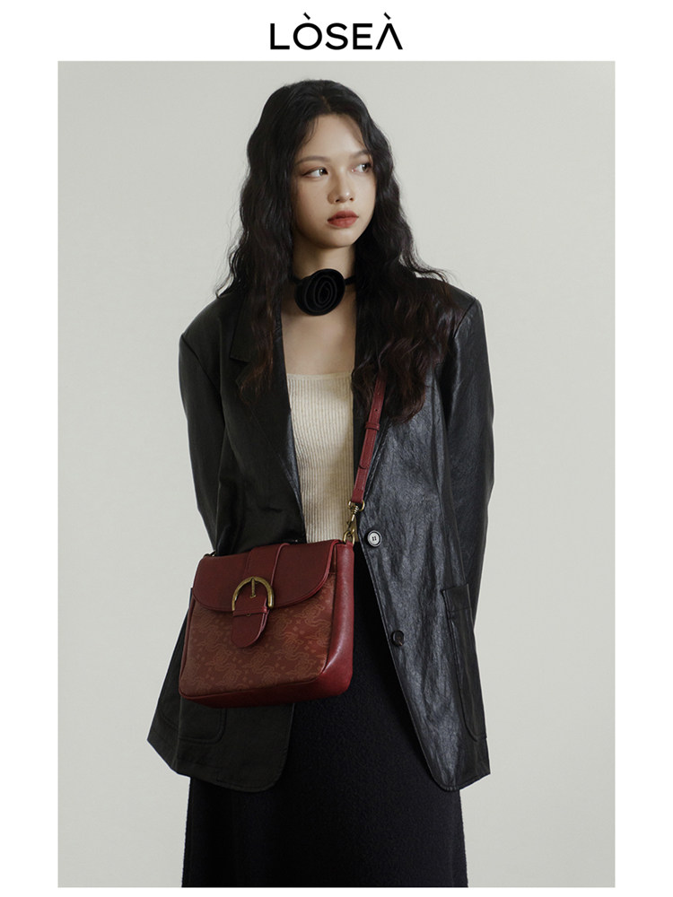 Woman wearing a black blazer and carrying a red shoulder bag