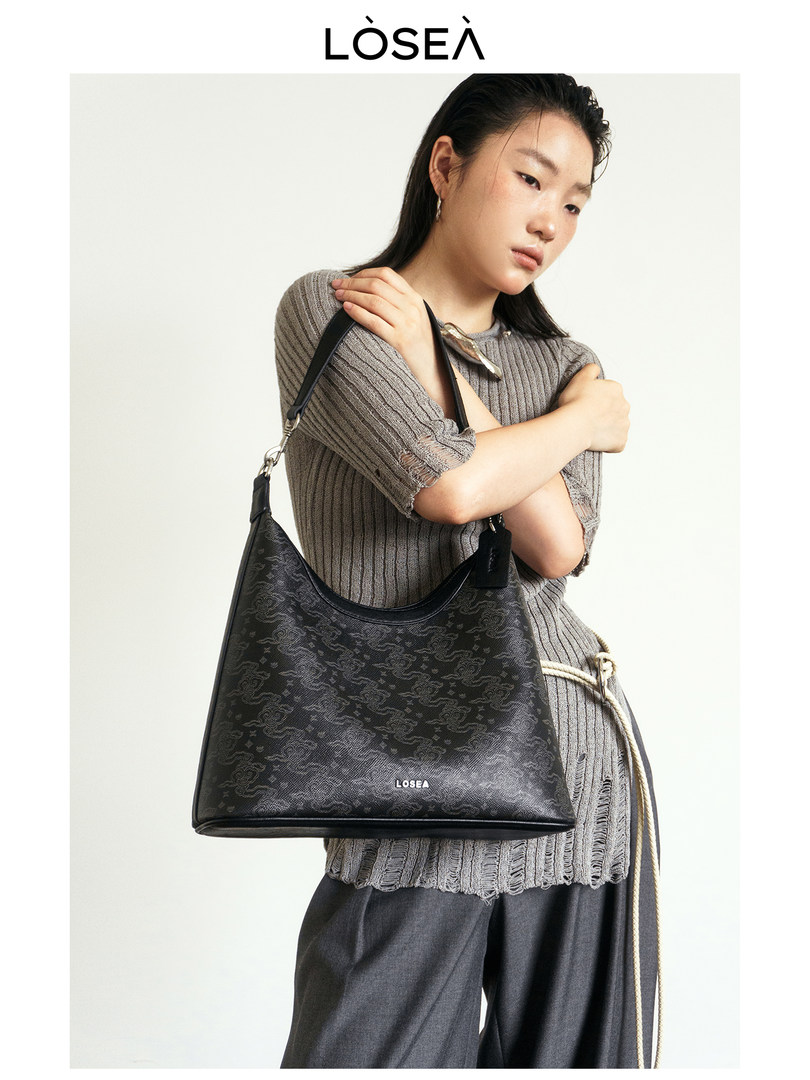 Black patterned shoulder handbag worn by a model