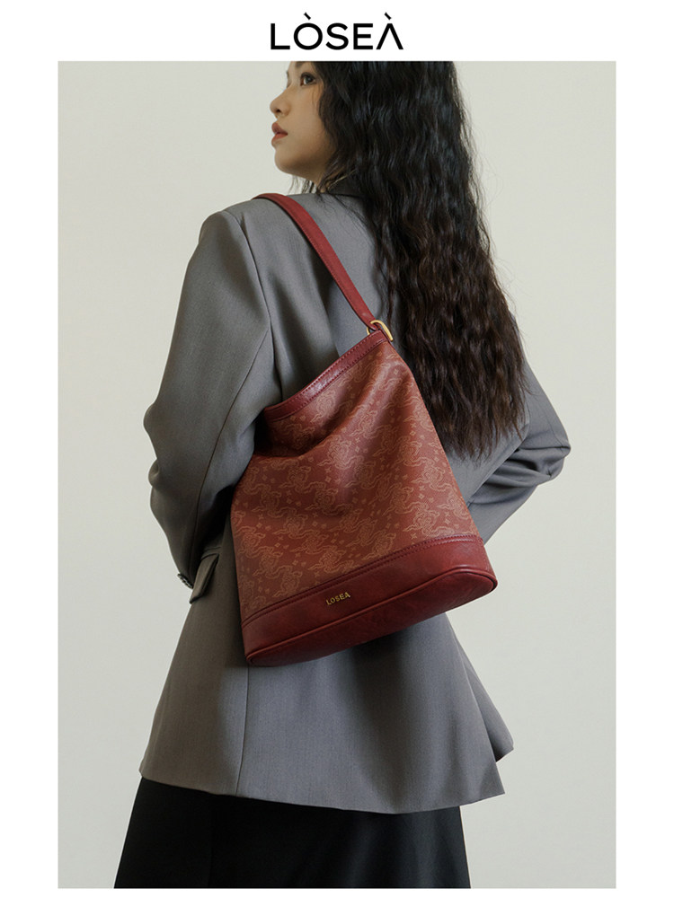 Woman wearing a red leather shoulder bag with a gray blazer