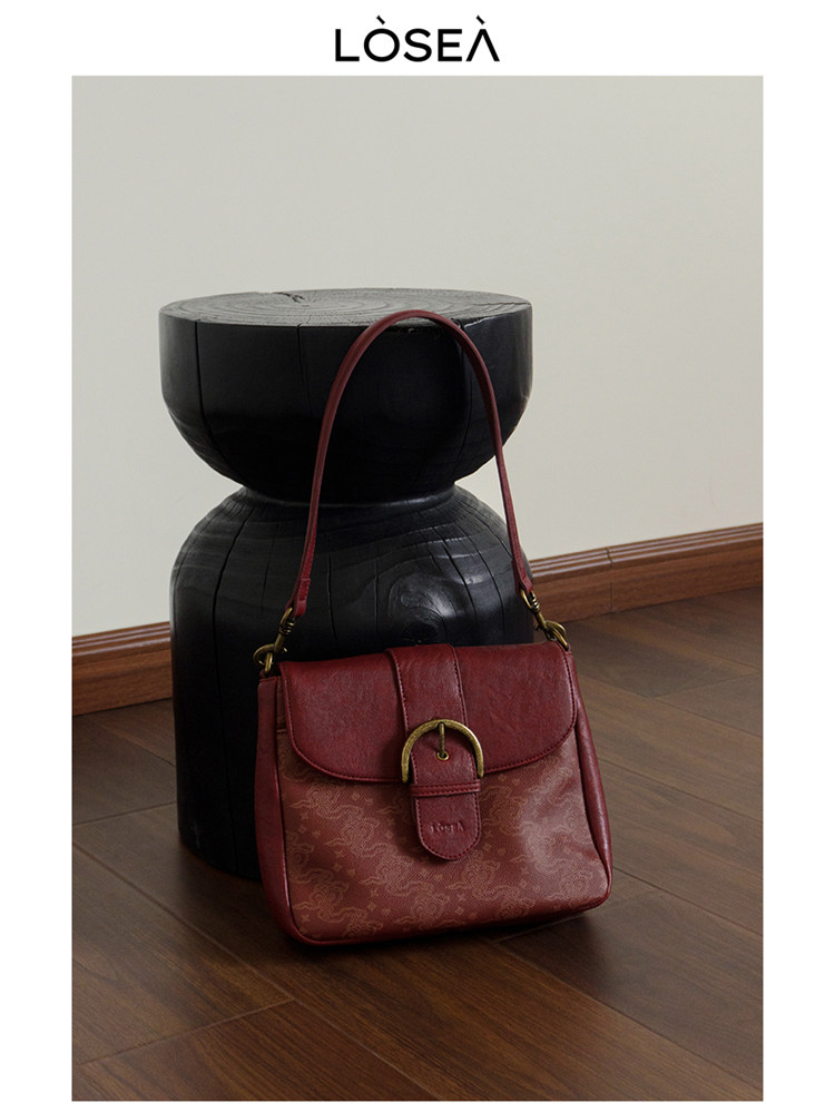 Red leather shoulder handbag on a studio floor backdrop