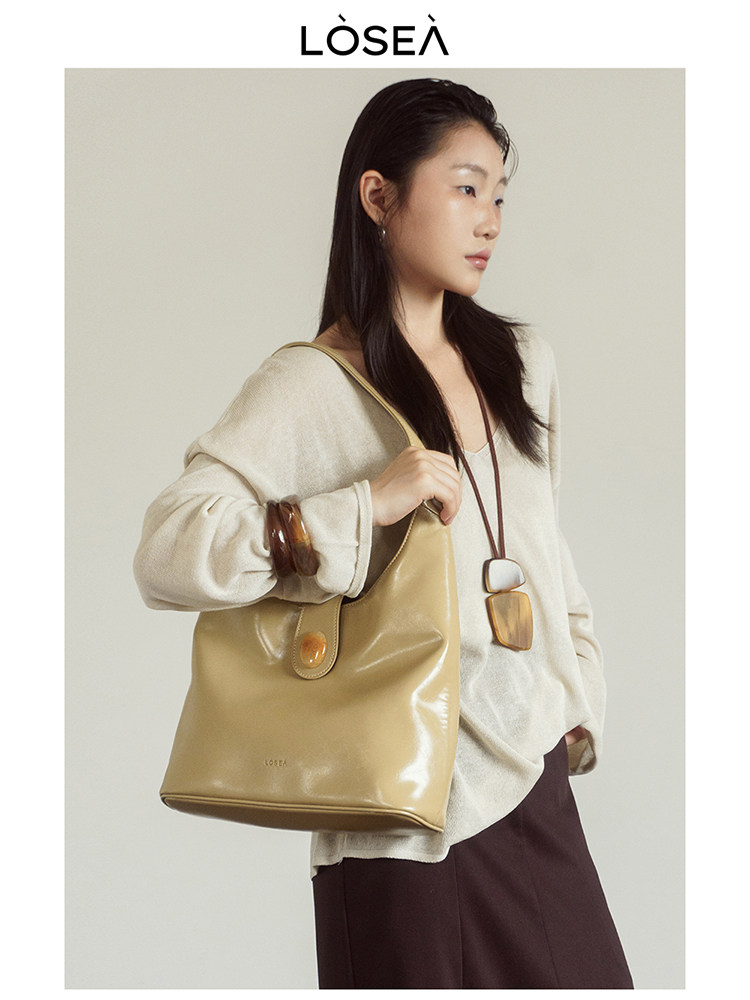 Model wearing a beige leather tote handbag