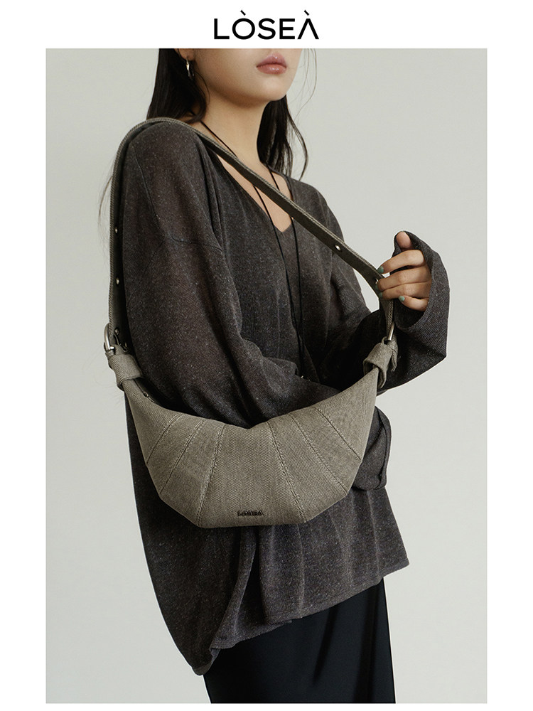 Gray crescent shoulder bag worn crossbody by a model