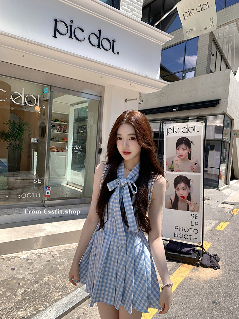Woman wearing a blue gingham sleeveless bow dress outdoors