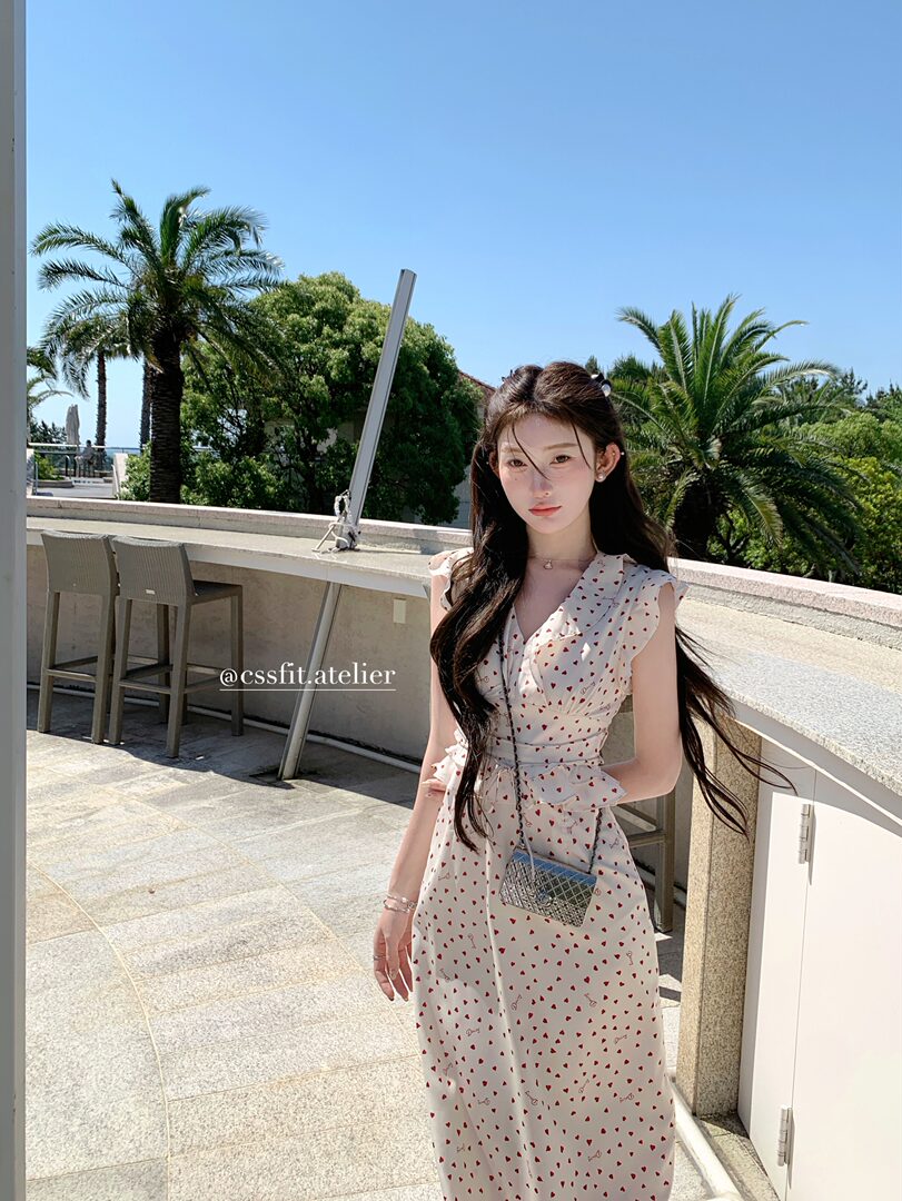Woman wearing a white heart-print dress outdoors on a sunny terrace