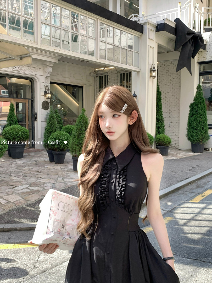 Model wearing a black sleeveless ruffled dress outdoors
