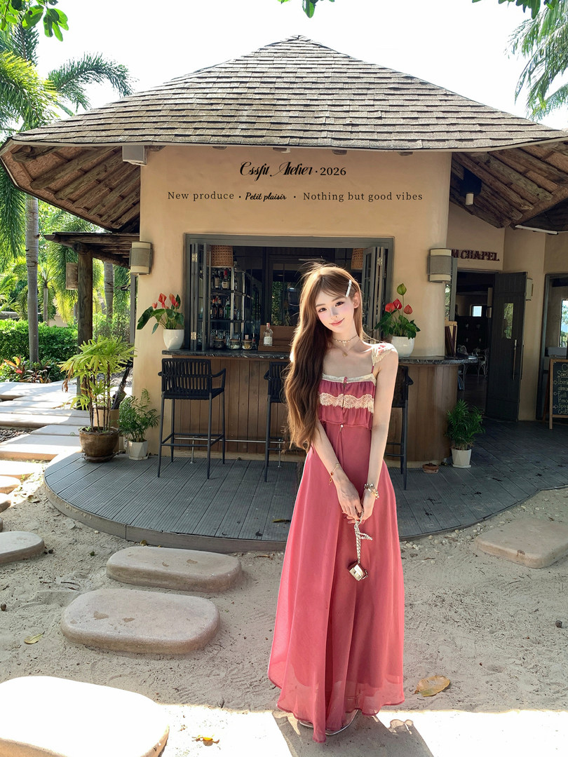 Pink sleeveless maxi dress worn by a model outdoors in a tropical resort setting