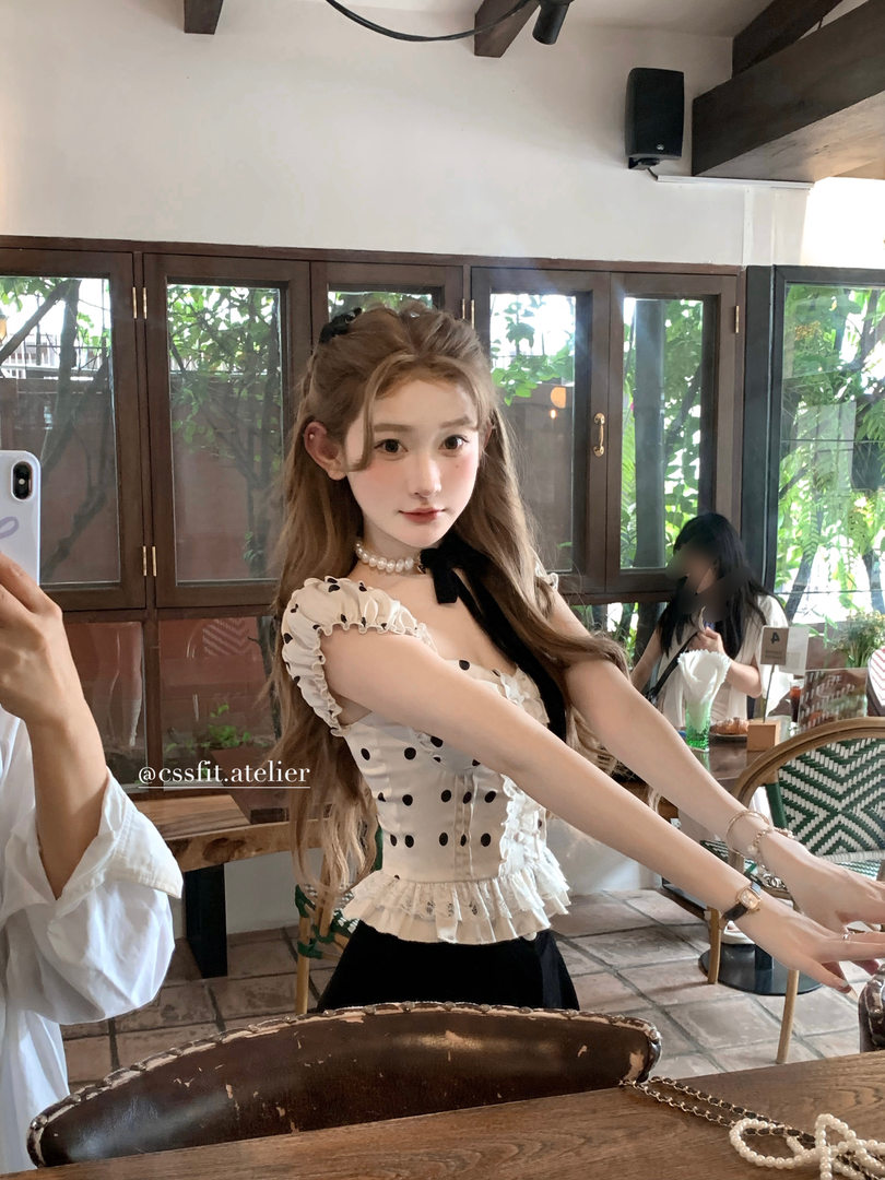 Woman wearing a white polka dot ruffled sleeveless peplum top