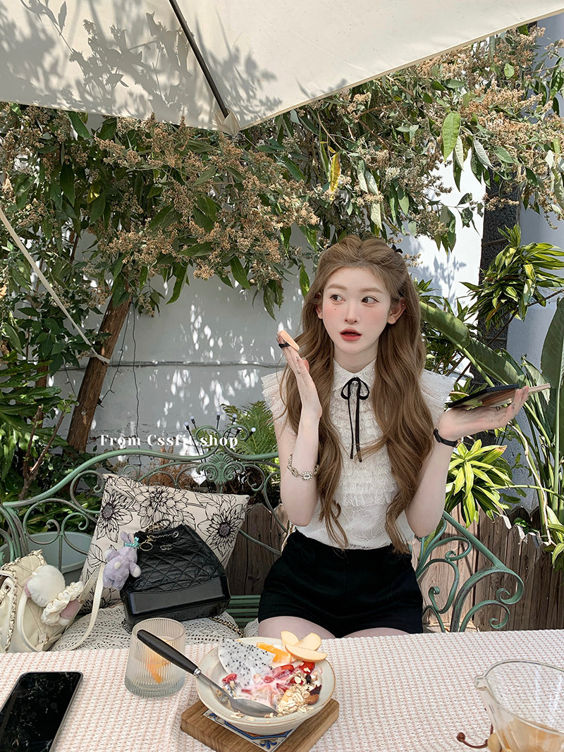 Woman wearing a white sleeveless blouse and black skirt at an outdoor café