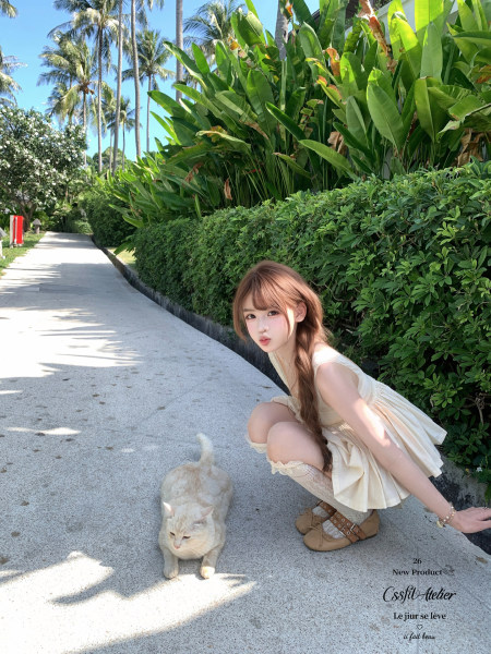 Woman wearing a cream sleeveless dress and brown shoes outdoors in a tropical setting