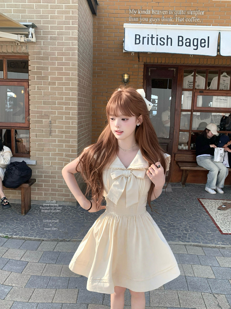 Model wearing a cream sleeveless bow-front dress outdoors