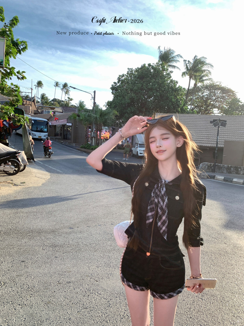 Woman wearing a black top and plaid-trimmed shorts on a sunny street