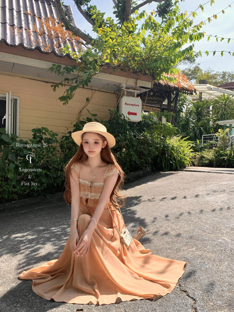 Woman wearing a peach lace-trim maxi dress and straw hat outdoors