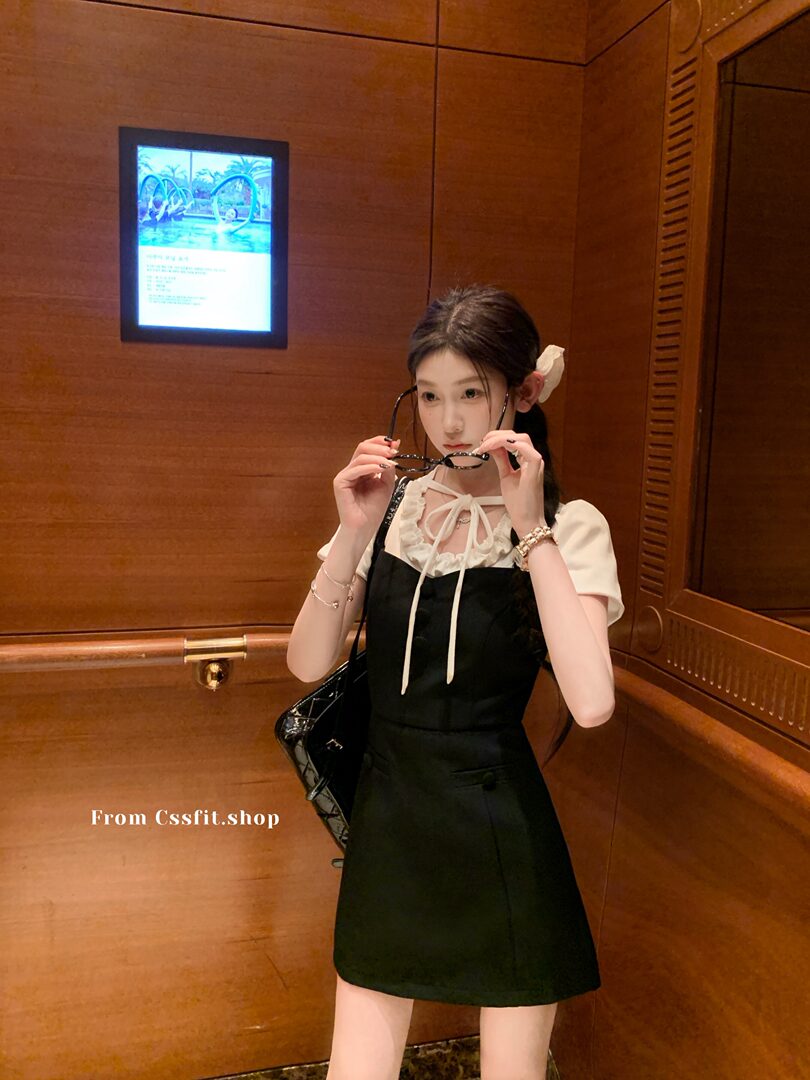 Woman wearing a black pinafore dress over a white top
