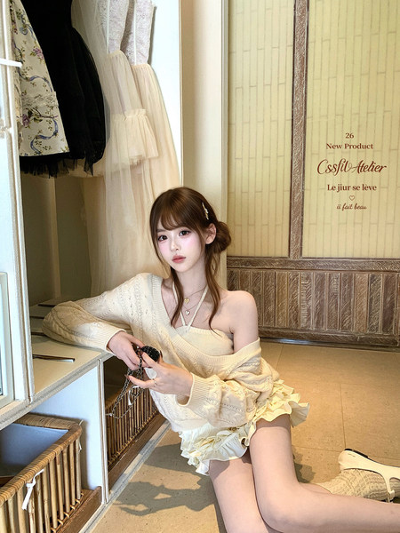 Woman wearing a cream off-shoulder knit sweater with a ruffled mini skirt