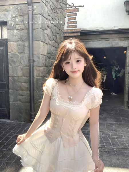 Model wearing a cream lace corset-style dress with layered skirt