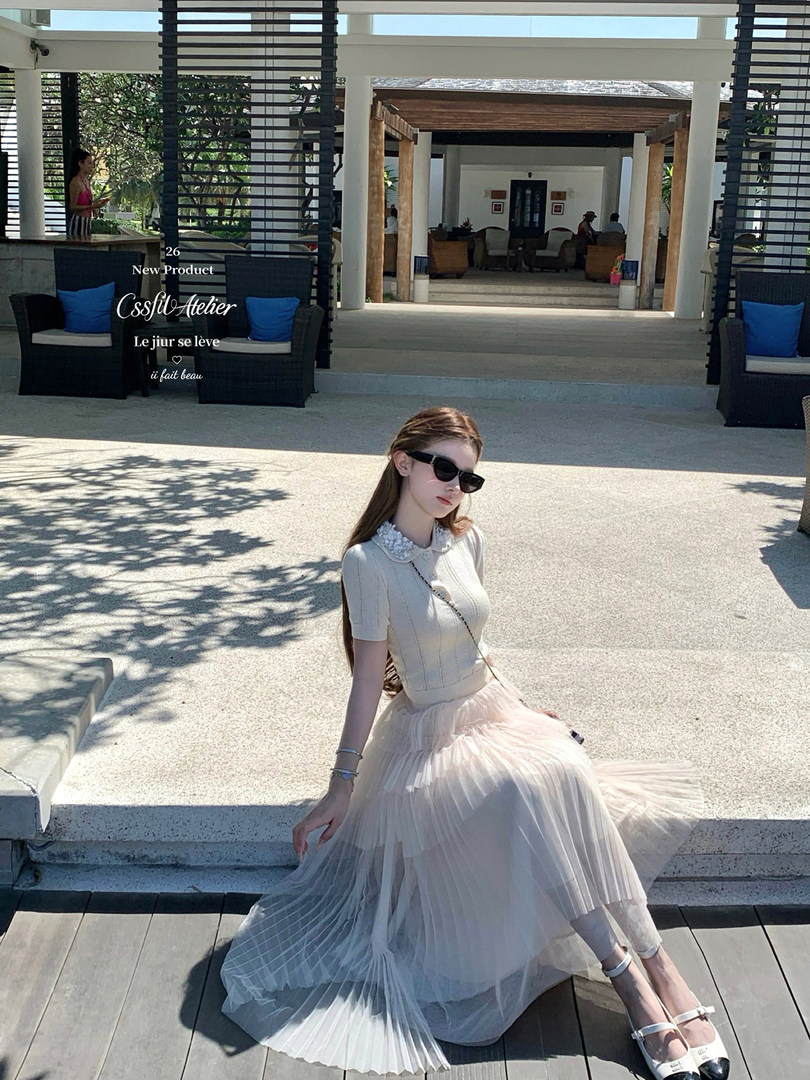 Woman wearing a cream knit top with a flowing tulle skirt and sunglasses