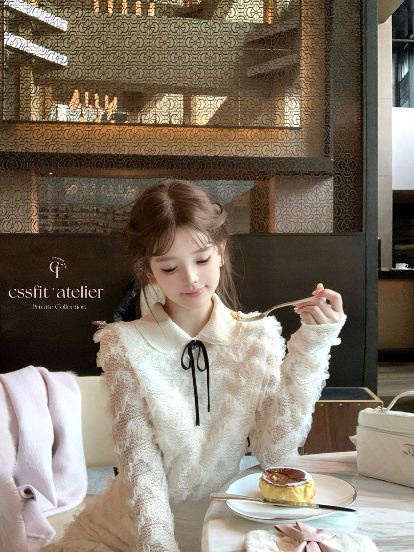 White lace dress with ribbon bow worn by a model at a café table