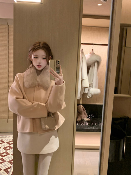 Woman wearing a beige coat with a large fur collar in a mirror selfie