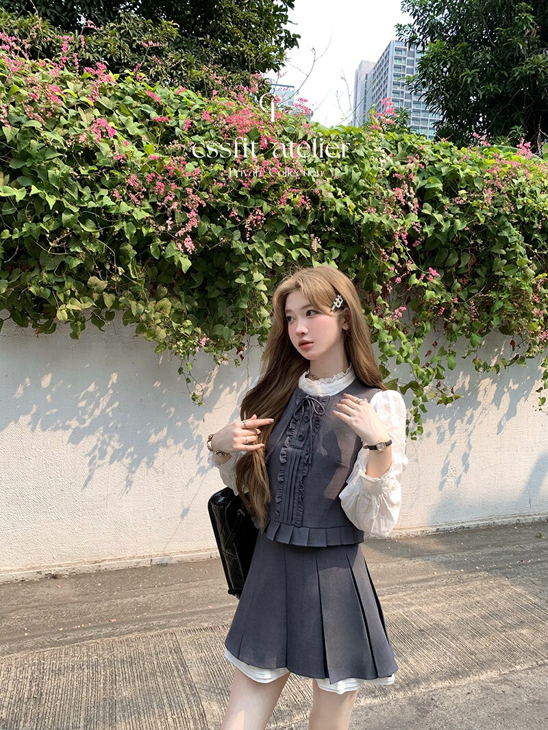 Young woman wearing a gray pleated dress set with a white blouse outdoors