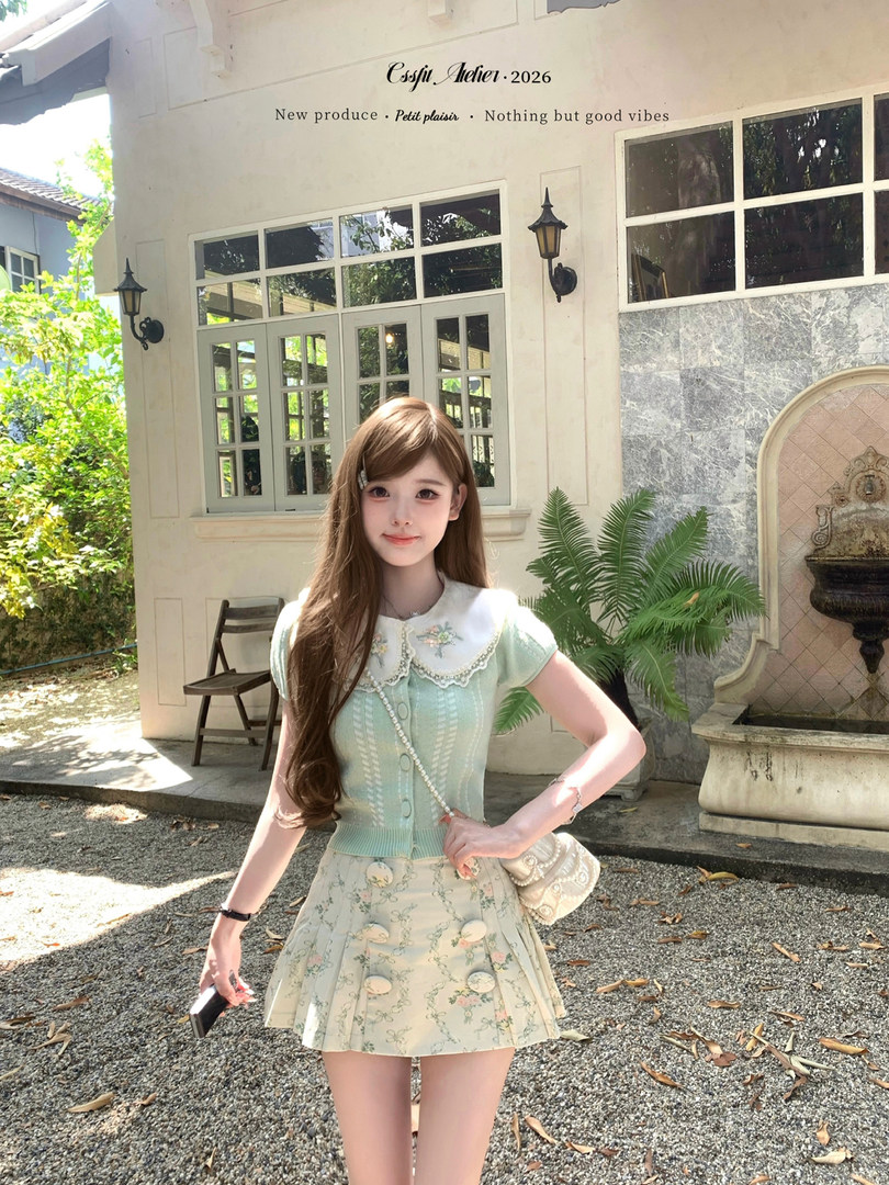 Model wearing a pastel mint knit top and floral pleated mini skirt outdoors