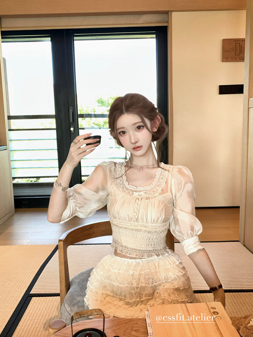 Woman wearing a cream lace puff-sleeve dress seated indoors