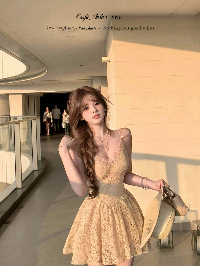 Woman wearing a beige lace sleeveless dress and holding a hat and handbag