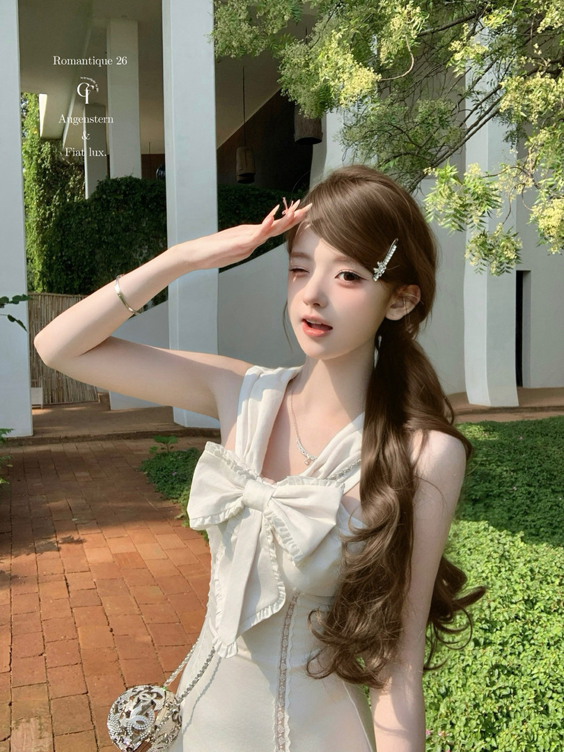 Woman wearing a white sleeveless dress with a large bow outdoors