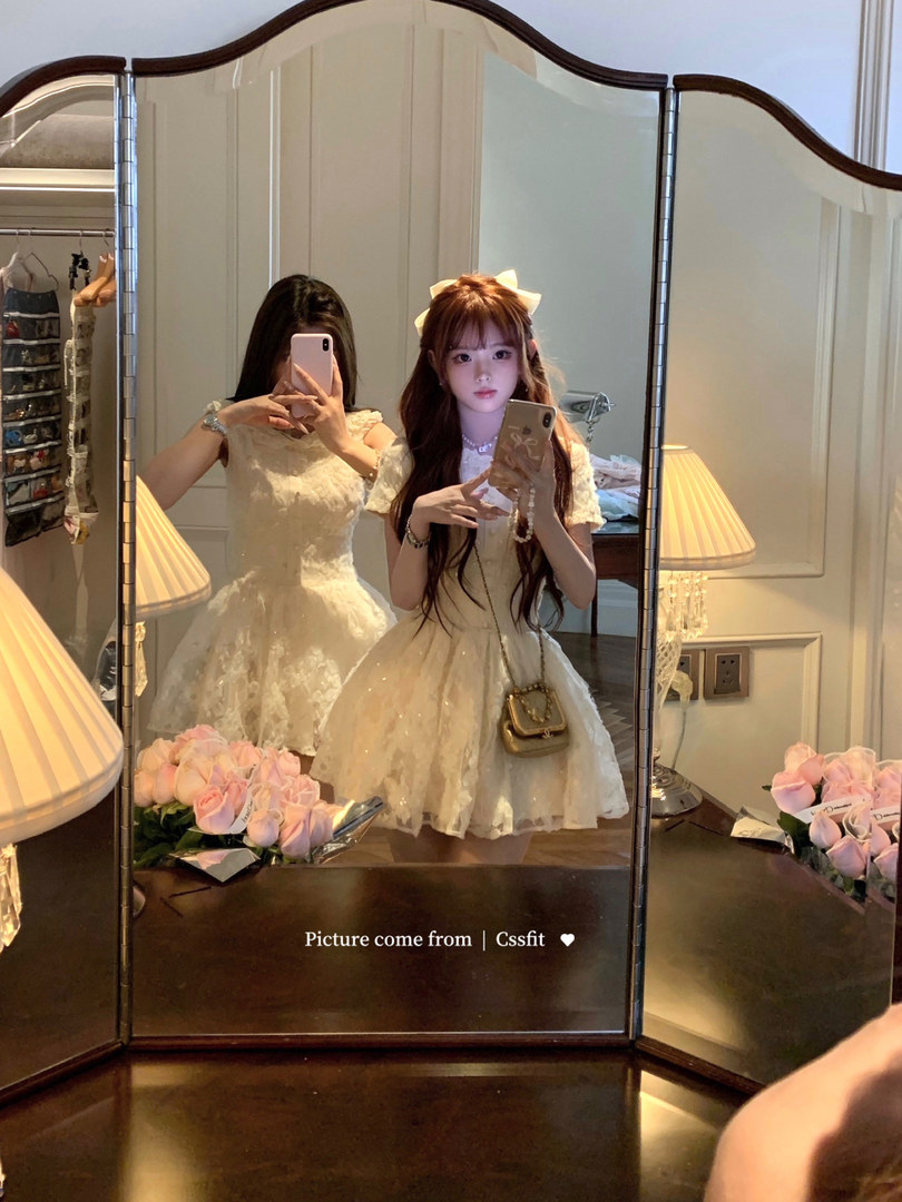 Woman wearing a cream lace mini dress in a mirror selfie