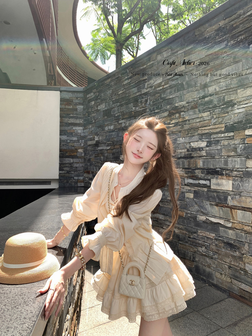 Woman wearing a cream ruffled dress with a small quilted crossbody bag and straw hat