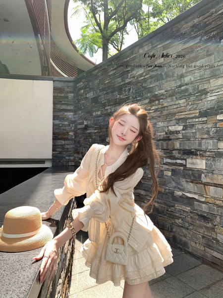 Woman wearing a cream ruffled dress with a small quilted crossbody bag and straw hat