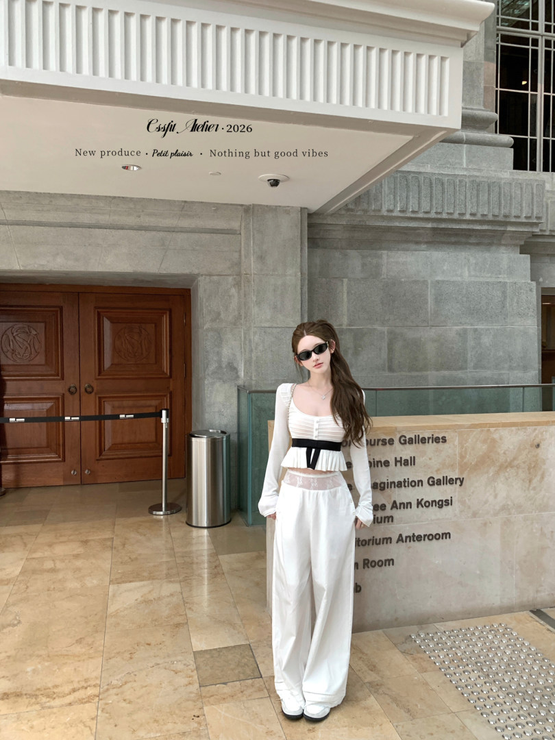 Woman wearing a white long-sleeve crop top and wide-leg pants with black sunglasses