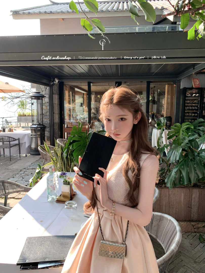 Woman wearing a light beige sleeveless dress at an outdoor restaurant