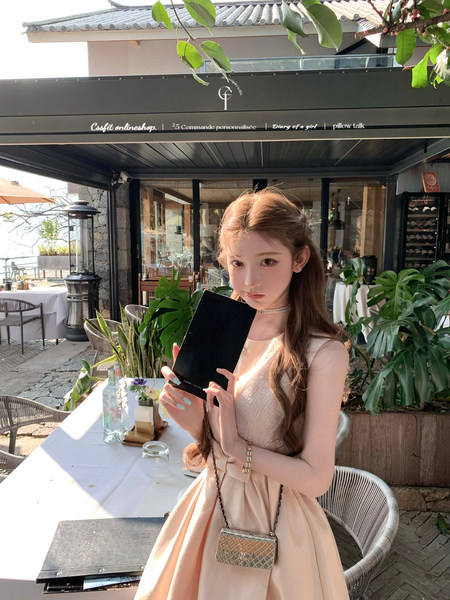 Woman wearing a light beige sleeveless dress at an outdoor restaurant