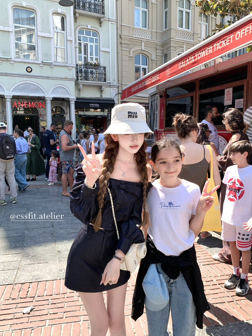 Two girls wearing a navy dress and casual white tee with jeans on a sunny street