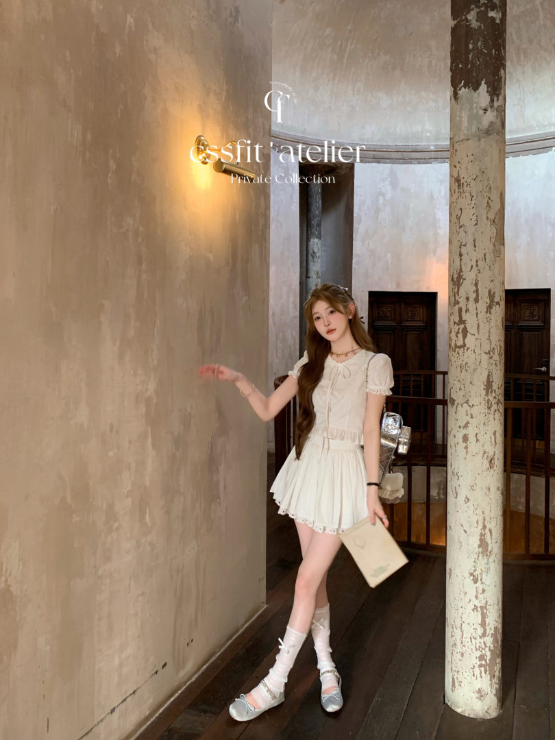 Woman wearing a white short-sleeve pleated dress with bow detail and sandals