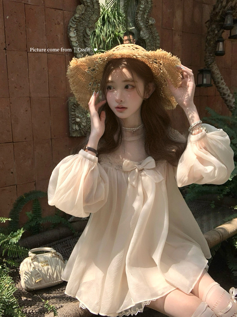 Woman wearing a cream chiffon dress with puff sleeves and a straw hat