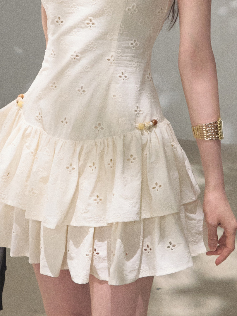 White sleeveless ruffled mini dress worn by a model