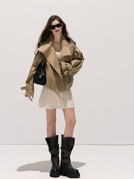 Model wearing a beige trench coat with lace shorts and black boots