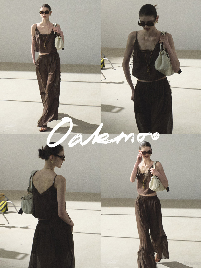 Model wearing a brown camisole top and loose pants with a light handbag
