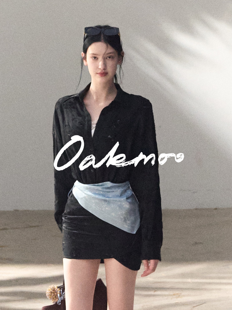 Model wearing a black shirt with a black mini skirt and light blue wrap detail