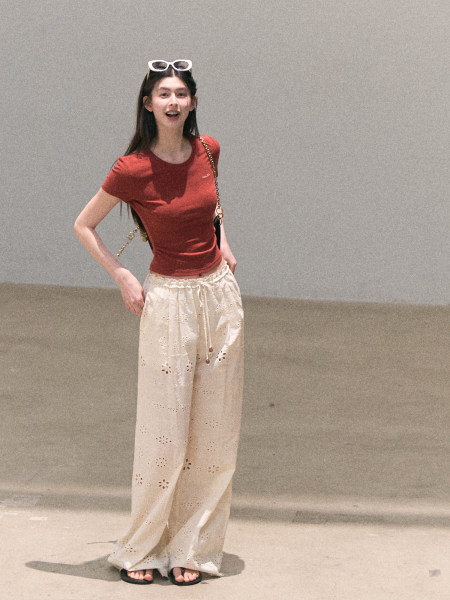 Model wearing a red fitted T-shirt and cream eyelet wide-leg pants
