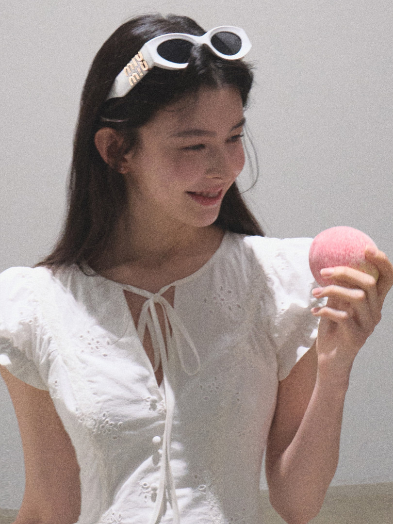 Woman wearing a white embroidered blouse with white sunglasses